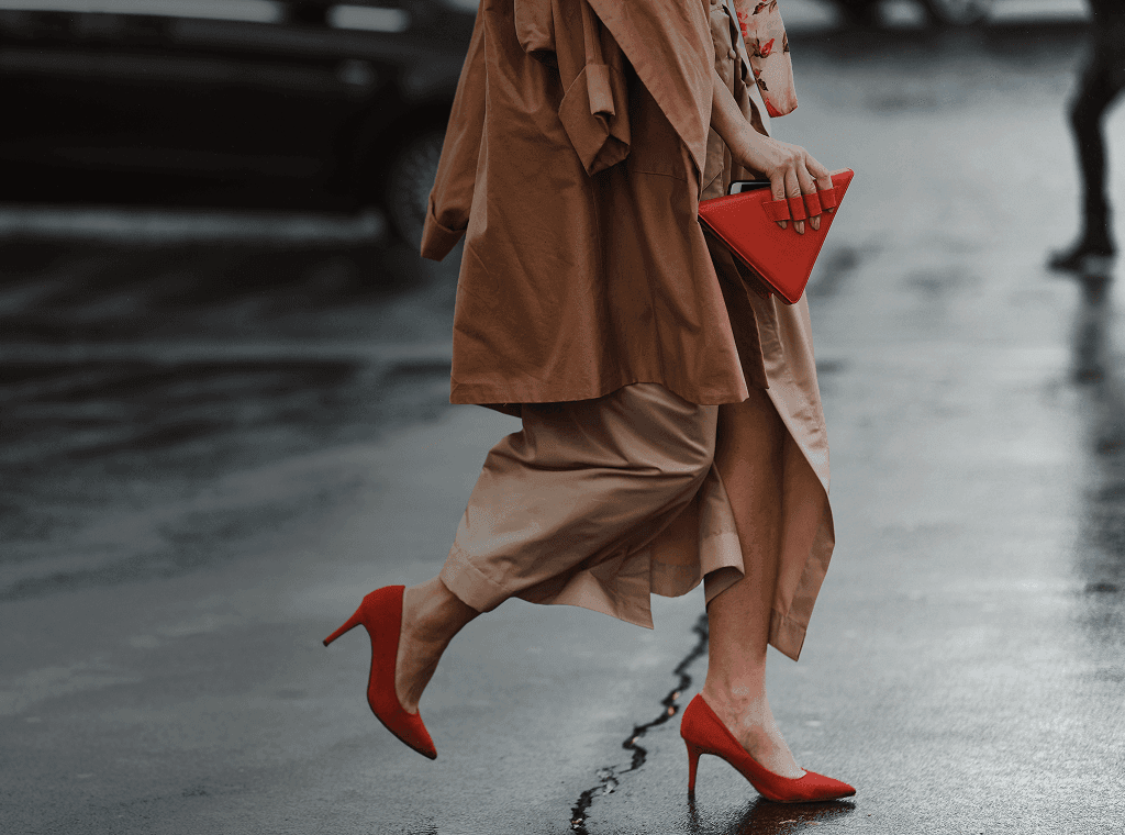 Una donna ben vestita, con dei bellissimi tacchi rossi e una borsa rossa alla moda, attraversa la strada. Sovrapposta la frase francese "bien habillé" con la sua traduzione in italiano, "ben vestita".