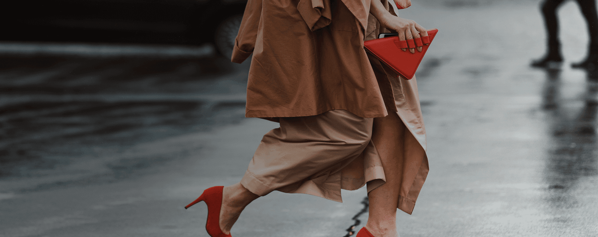 Una donna ben vestita, con dei bellissimi tacchi rossi e una borsa rossa alla moda, attraversa la strada. Sovrapposta la frase francese "bien habillé" con la sua traduzione in italiano, "ben vestita".