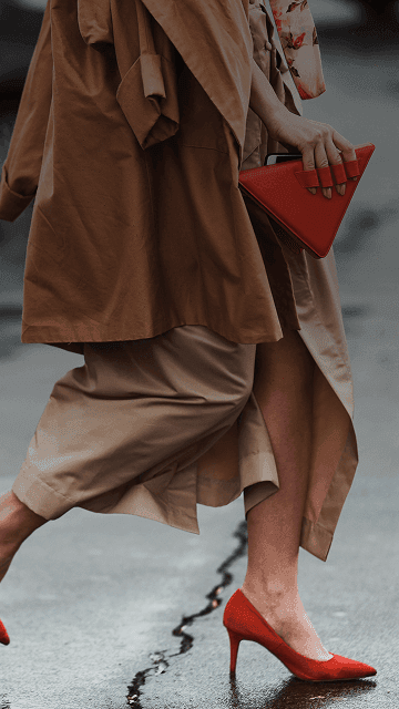Una donna ben vestita, con dei bellissimi tacchi rossi e una borsa rossa alla moda, attraversa la strada. Sovrapposta la frase francese "bien habillé" con la sua traduzione in italiano, "ben vestita".
