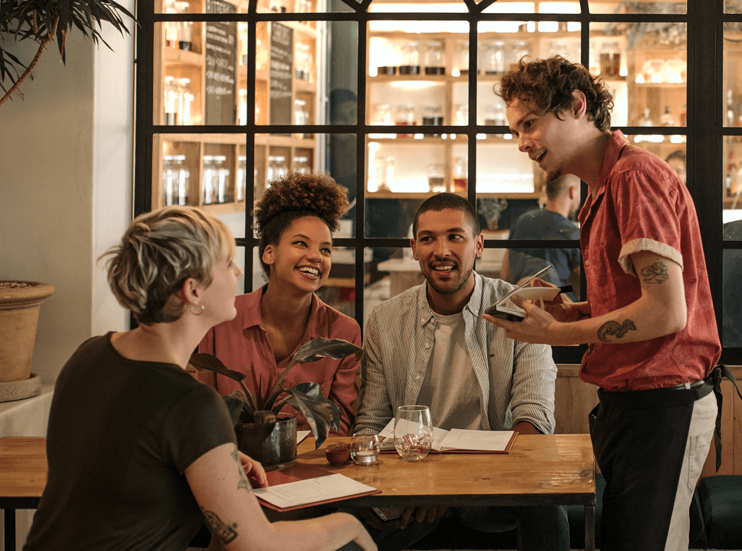 Un gruppo di amici mette in pratica una nuova lingua imparata mentre ordinano da un cameriere in un elegante bar.