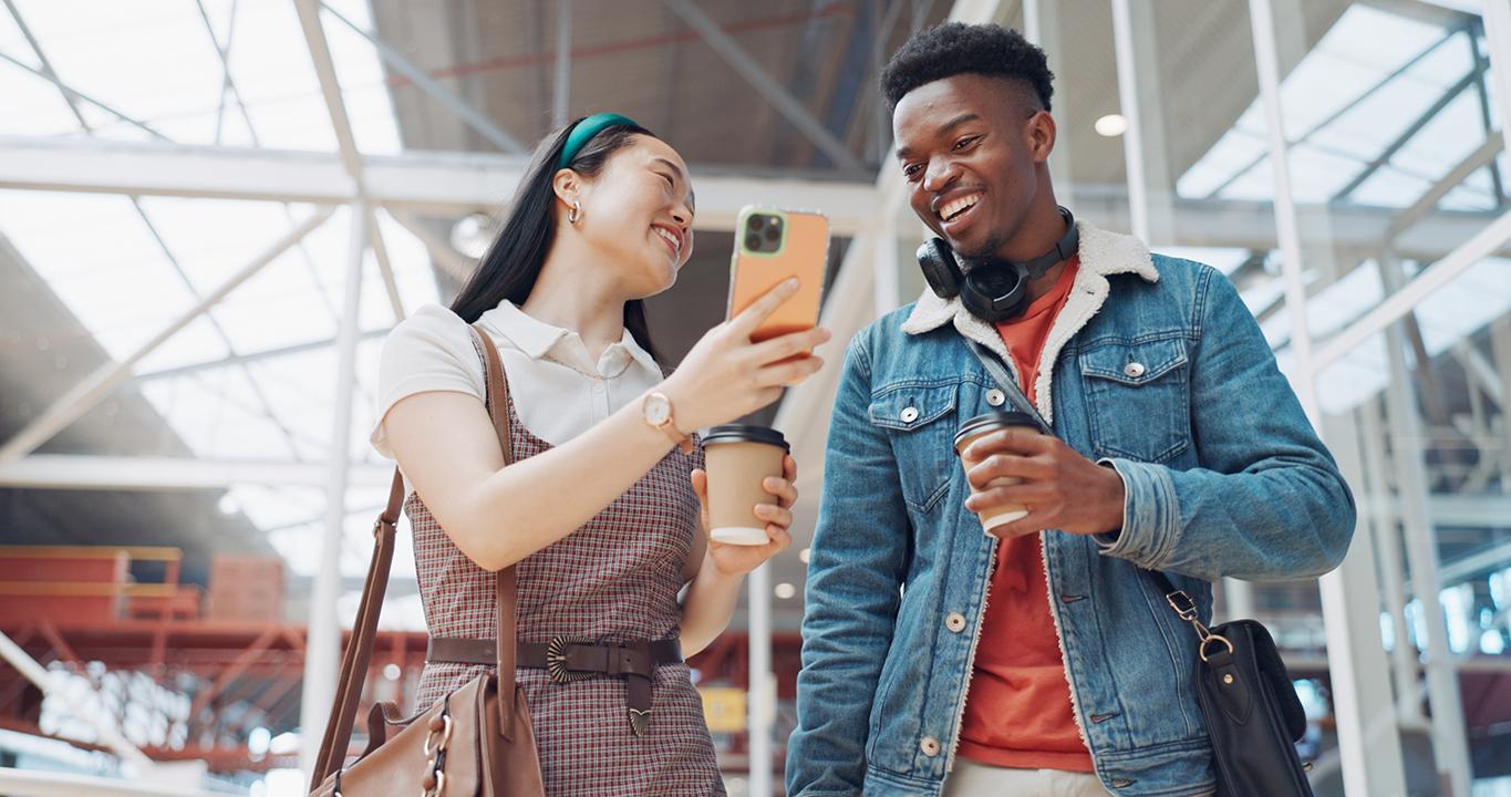 Due studenti sorridenti che guardano uno smartphone; rappresentano le soluzioni per l'apprendimento delle lingue di Rosetta Stone per le scuole che promuovono un tipo di apprendimento interattivo e mobile.